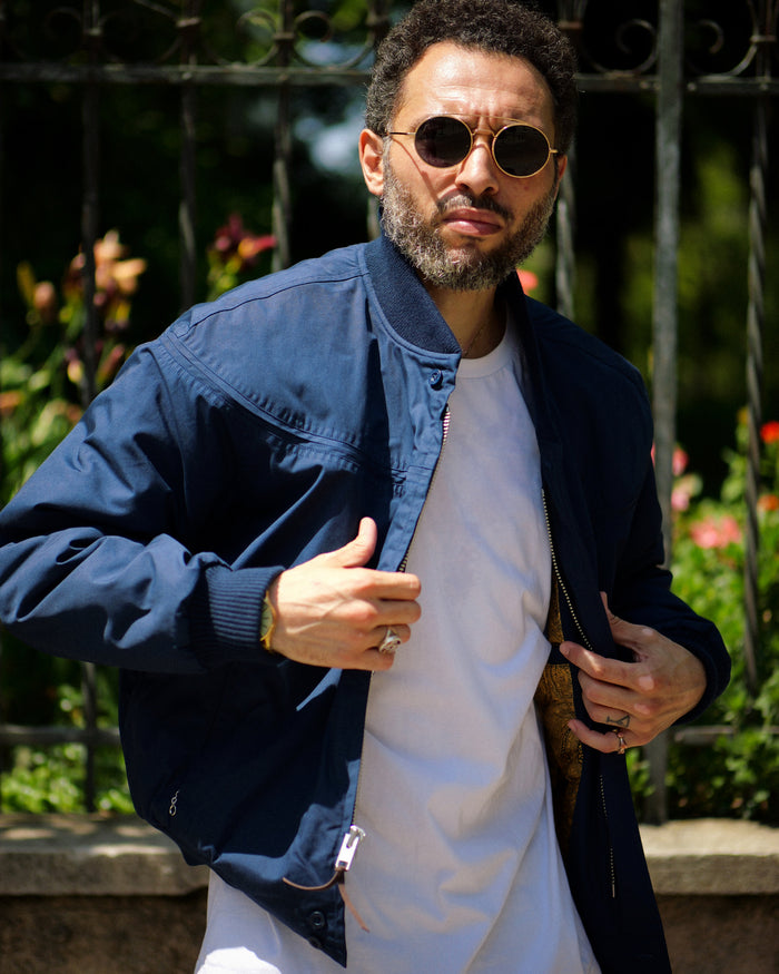 Man wearing sunglasses and a blue jacket with a blurred background