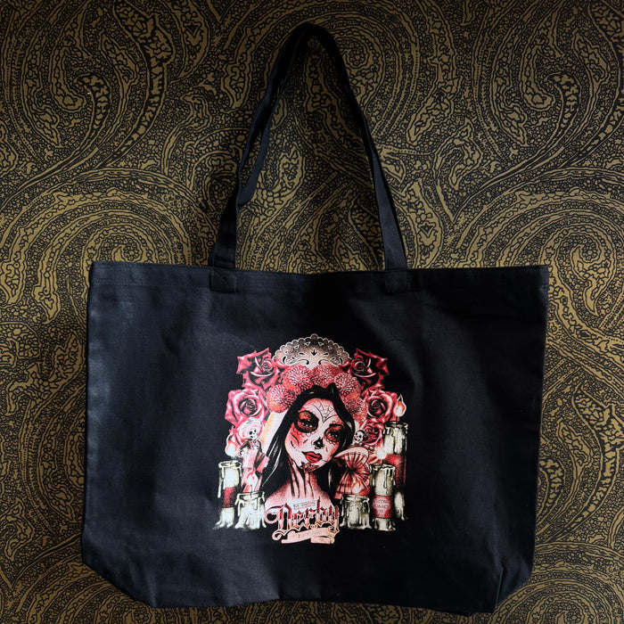 Black tote bag with a colorful graphic design on a patterned background