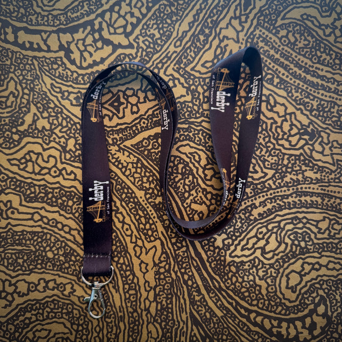 Black lanyard with a brand logo on a patterned fabric background